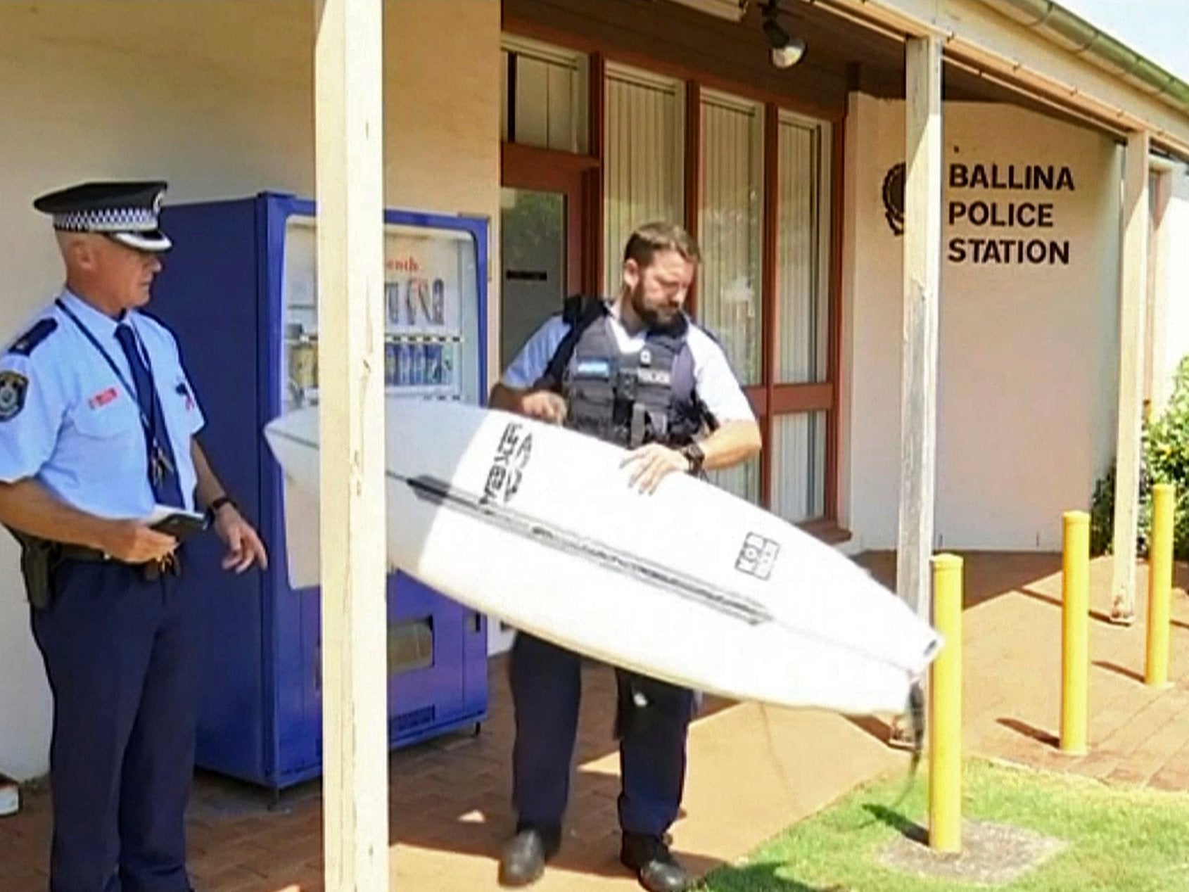 Police officer holds a victim's surfboard at a police station in Ballina, Australia