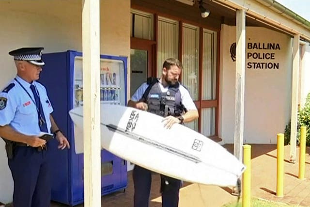 Police officer holds a victim's surfboard at a police station in Ballina, Australia