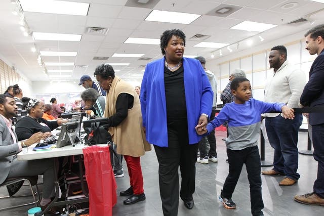 Stacey Abrams walks to a voting machine with her nephew in Decatur, Georgia