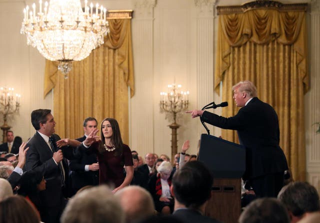 A White House staff member reaches for the microphone held by CNN's Jim Acosta as he questions Donald Trump