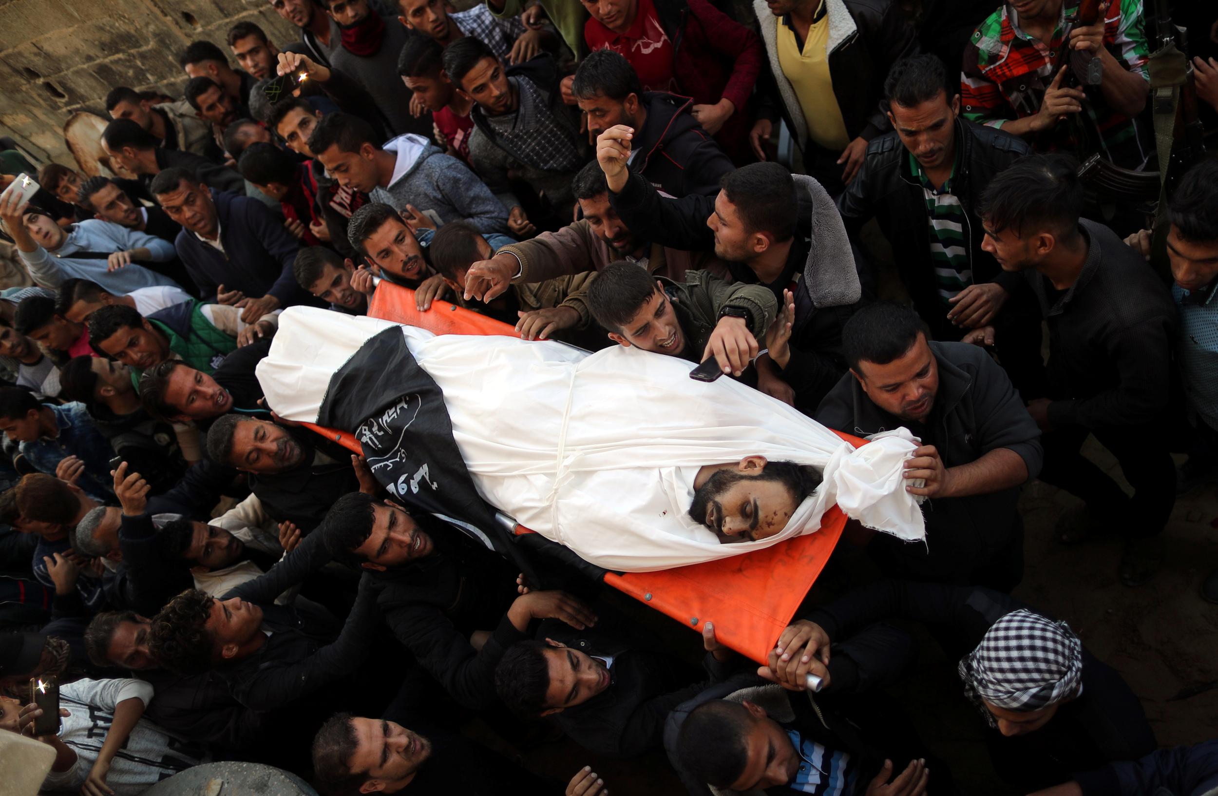 Mourners carry the body of Palestinian Khaled Qwaider, who was killed in an Israeli air strike, during his funeral, in Khan Younis in the southern Gaza Strip