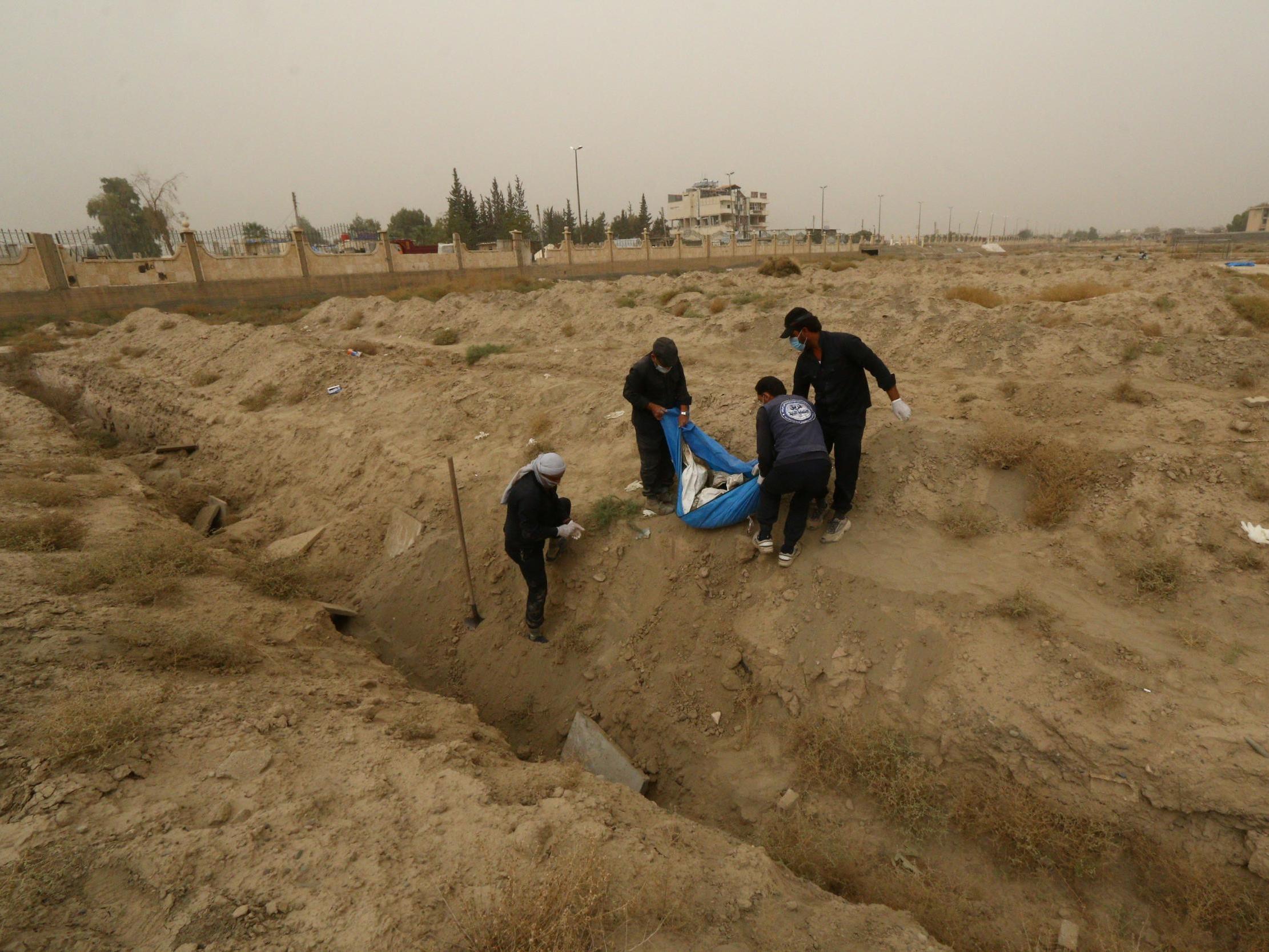 People work at a mass grave in Raqqa, Syria on 16 October