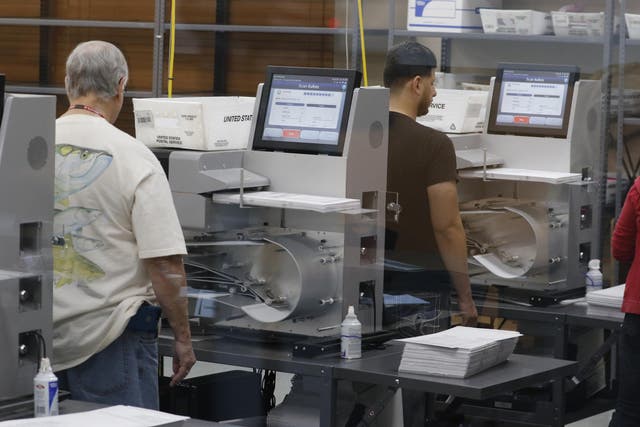 Florida elections staff load ballots into machines as the statewide vote recount is being conducted to determine the races for governor, Senate, and agriculture commissioner.