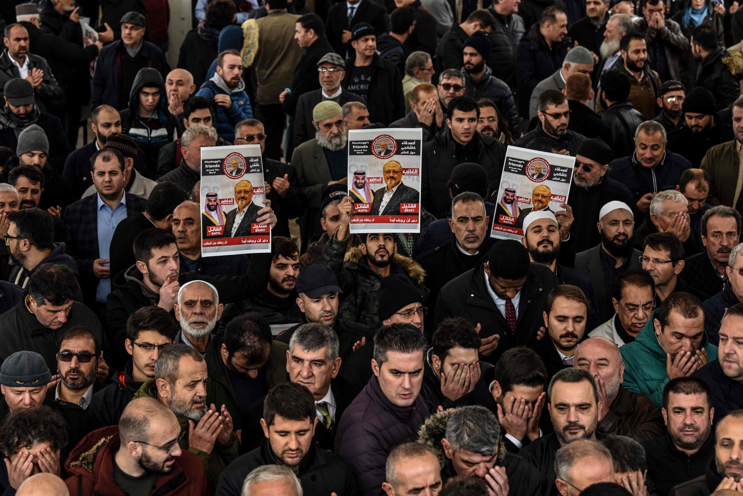 Mourners hold up posters at a funeral for murdered journalist Jamal Khashoggi in Istanbul