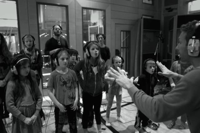 Chris Martin conducts a choir of children. The band's music has involved more choruses of voices in recent years