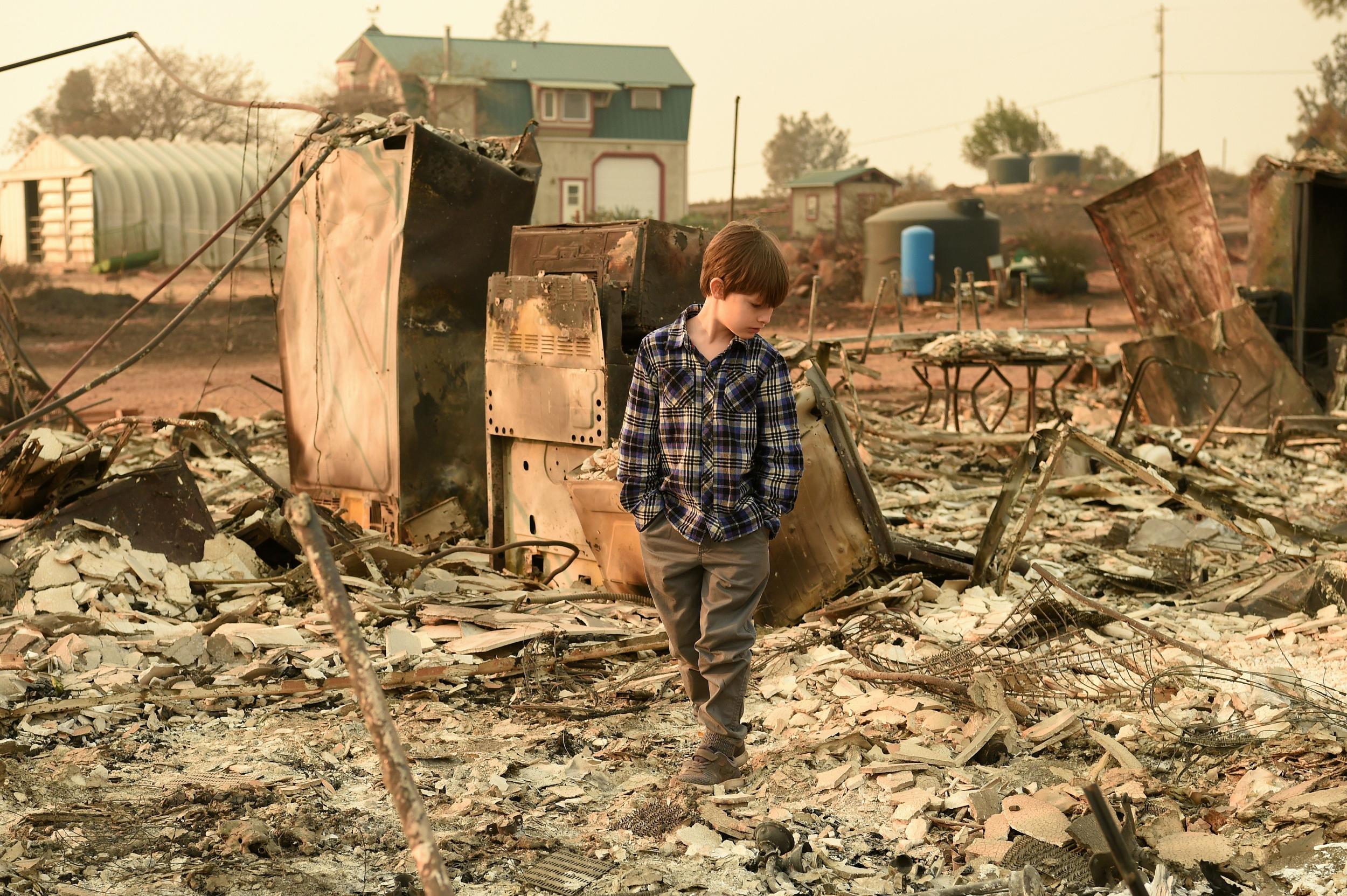 Jacob Saylors, 11, walks through the burned remains of his home in Paradise, California, on November 18, 2018 as the area may also get floods