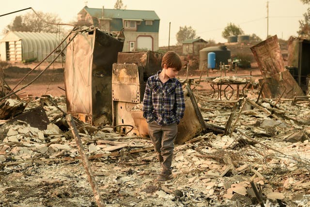 Jacob Saylors, 11, walks through the burned remains of his home in Paradise, California, on November 18, 2018 as the area may also get floods