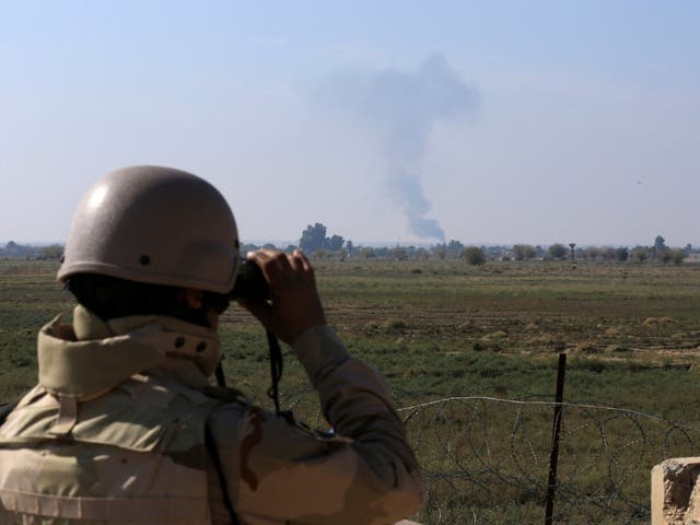 An Iraqi soldier watches smoke rising after an airstrike by US-led International coalition warplanes against ISIS, on the border between Syria and Iraq in Qaim, Anbar province, Iraq on 13 November 2018. (Hadi Mizban /