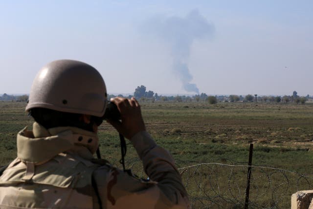 An Iraqi soldier watches smoke rising after an airstrike by US-led International coalition warplanes against ISIS, on the border between Syria and Iraq in Qaim, Anbar province, Iraq on 13 November 2018. (Hadi Mizban /