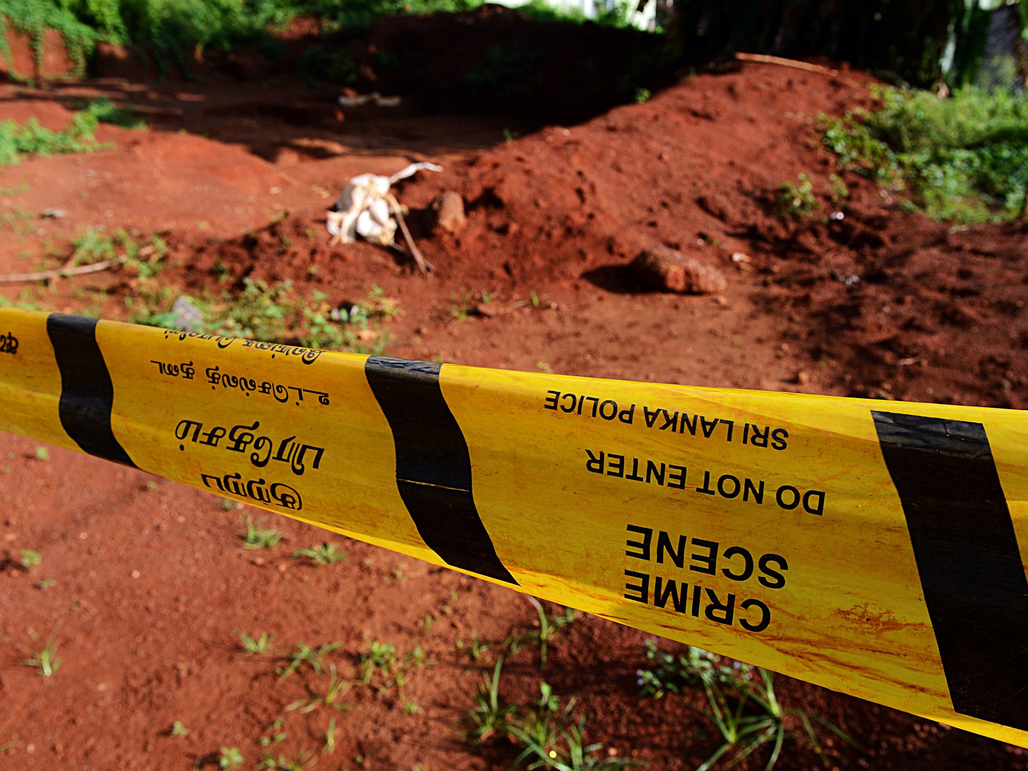 Police tape closes off part of a mass grave where authorities found skeletal remains of over 150 people at the Matale hospital compound in central Sri Lanka