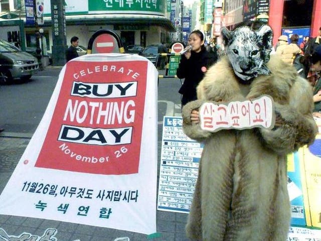 A member of a South Korean environmental protection group promotes International Buy Nothing Day in Seoul. The placard reads: 'I want to live'