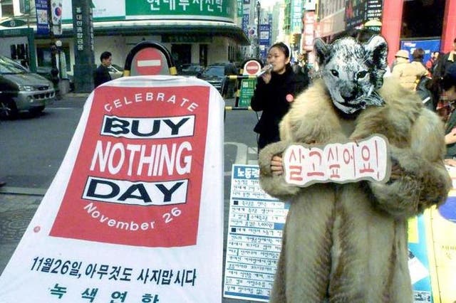 A member of a South Korean environmental protection group promotes International Buy Nothing Day in Seoul. The placard reads: 'I want to live'