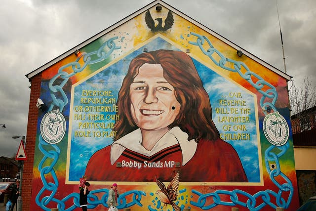 A couple walks past a mural of Bobby Sands in the Falls Road, Belfast. Republican Sands died in prison in 1981 after a 66-day hunger strike