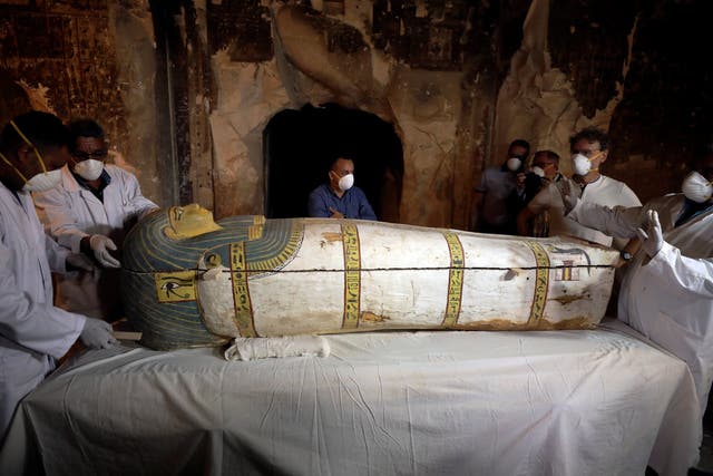 Archaeologists remove the cover of an intact sarcophagus inside a tomb in Luxor, Egypt 