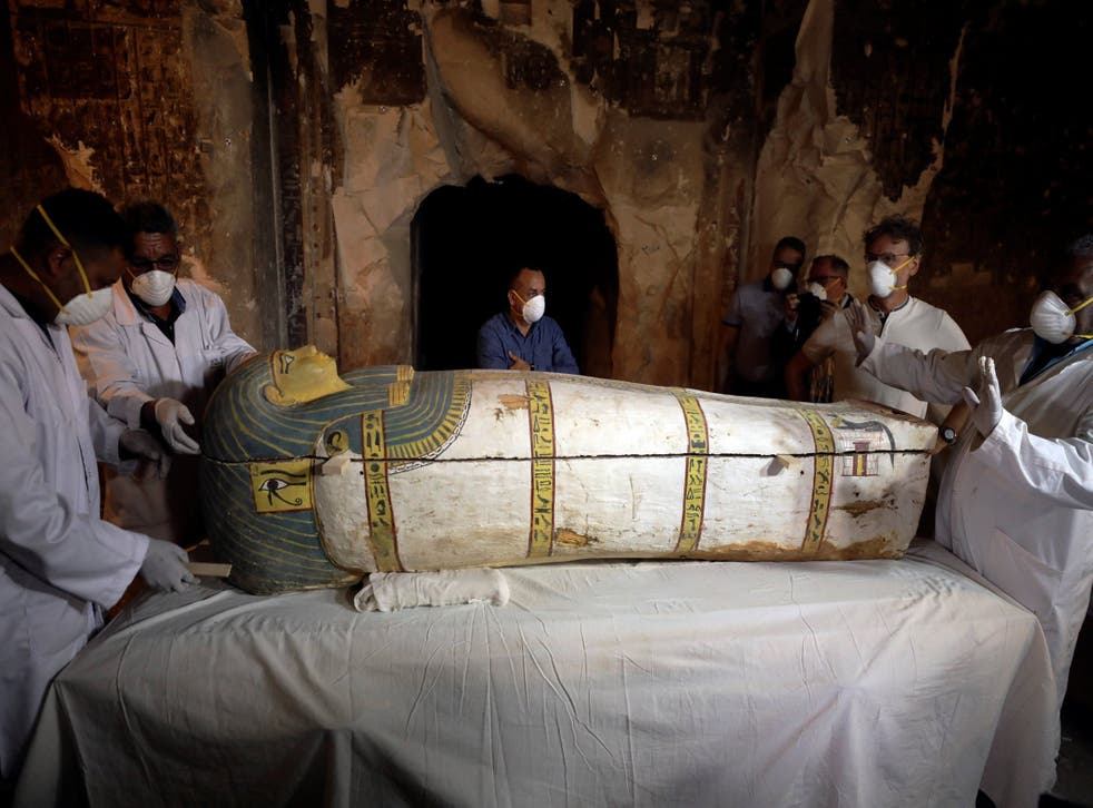 Archaeologists remove the cover of an intact sarcophagus inside a tomb in Luxor, Egypt 