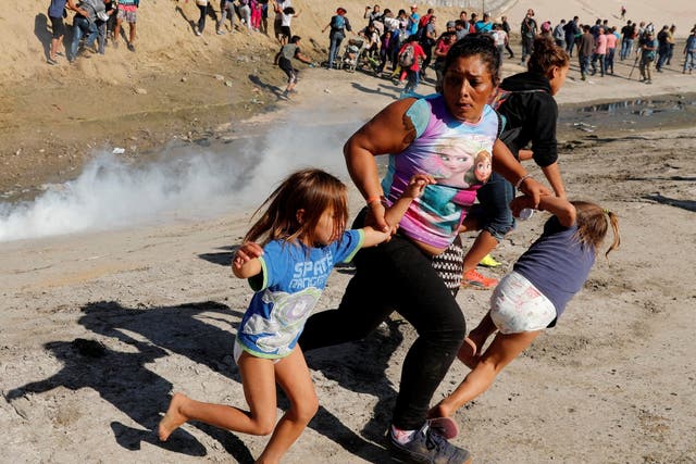 A migrant family from Honduras runs from tear gas fired by US border patrol at Mexico border