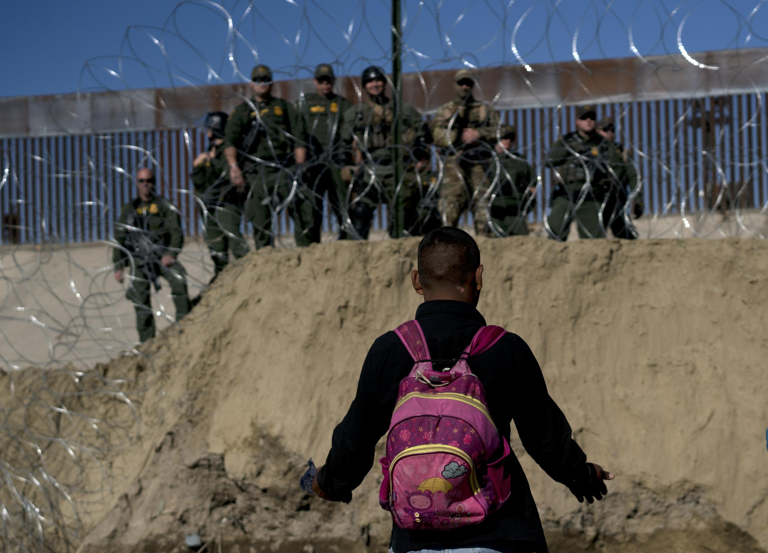 A Honduran migrant converses with US border agents on the other side of razor wire after they fired tear gas at migrants pressuring to cross from Tijuana, Mexico