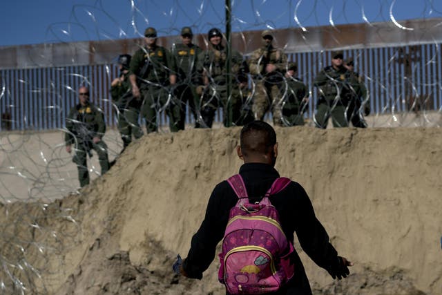 A Honduran migrant converses with US border agents on the other side of razor wire after they fired tear gas at migrants pressuring to cross from Tijuana, Mexico