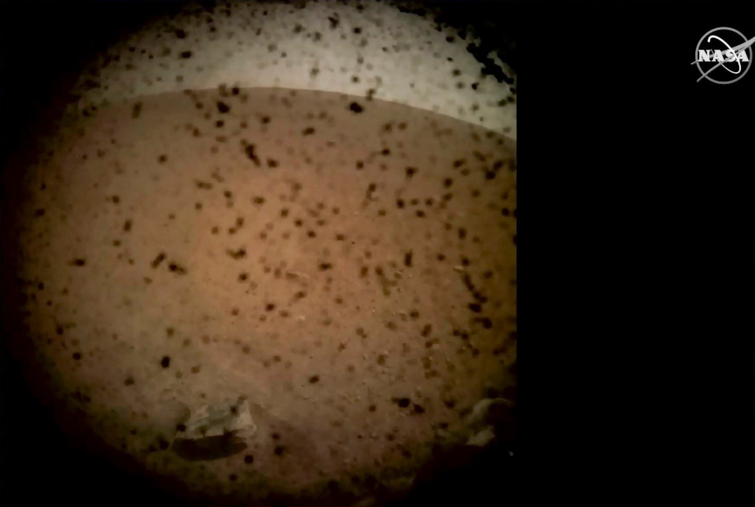 Debris is seen on the lens in the first image from Nasa’s InSight lander after it touched down on the surface of Mars