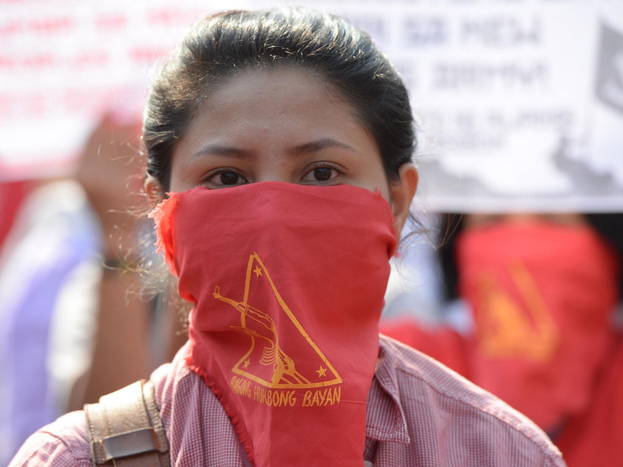 Supporters of the communist party of the Philippines’ armed group, the New People’s Army (NPA) with their faces covered march toward the peace arch for a protest near Malacanang Palace in Manila on 31 March 2017 (Ted Aljibe /