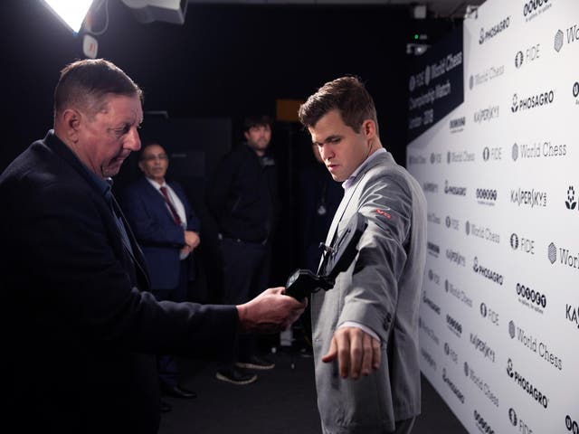 A member of security staff scans Magnus Carlsen as he enters the venue