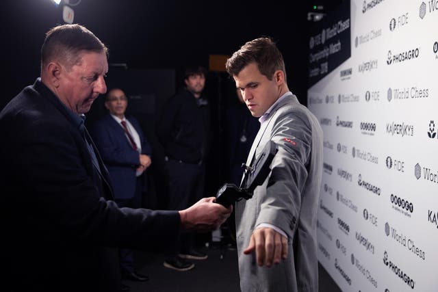 A member of security staff scans Magnus Carlsen as he enters the venue