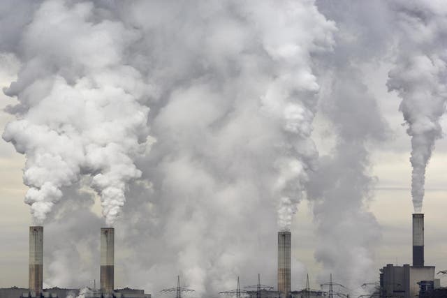 Smokestacks of a coal burning power plant with pollution on a cloudy day.