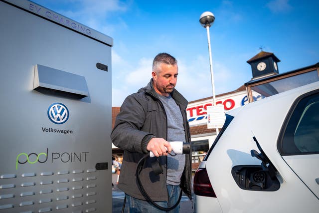 A man uses the free Pod Point electric charging point at Tesco in  Crawley