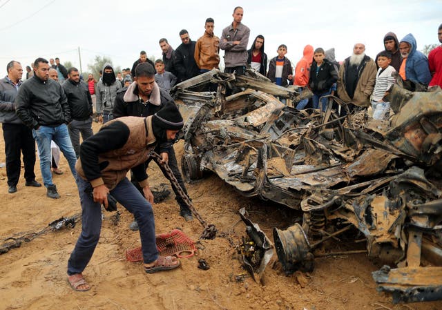 Palestinians inspect the remains of a vehicle that was destroyed in an Israeli air strike on Khan Younis after a botched intelligence raid