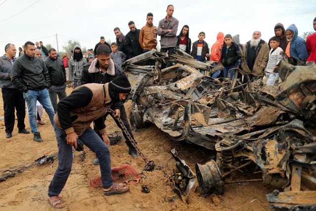 Palestinians inspect the remains of a vehicle that was destroyed in an Israeli air strike on Khan Younis after a botched intelligence raid