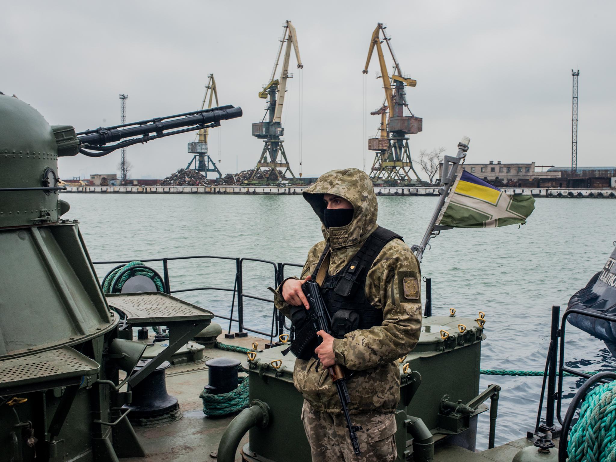 A Ukrainian border security force soldier guards an armed vessel in the Azov Sea