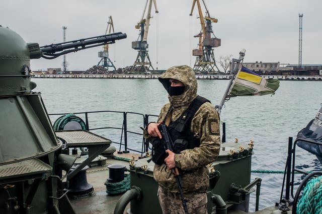A Ukrainian border security force soldier guards an armed vessel in the Azov Sea
