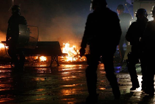 Riot police officers walk past a burning barricade amid protests in Paris