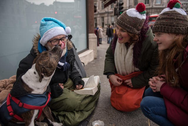 A woman and her daughter stop to talk to Paul, 49, and his dog Ben at Trafalgar Square on December 16, 2017 in London, England