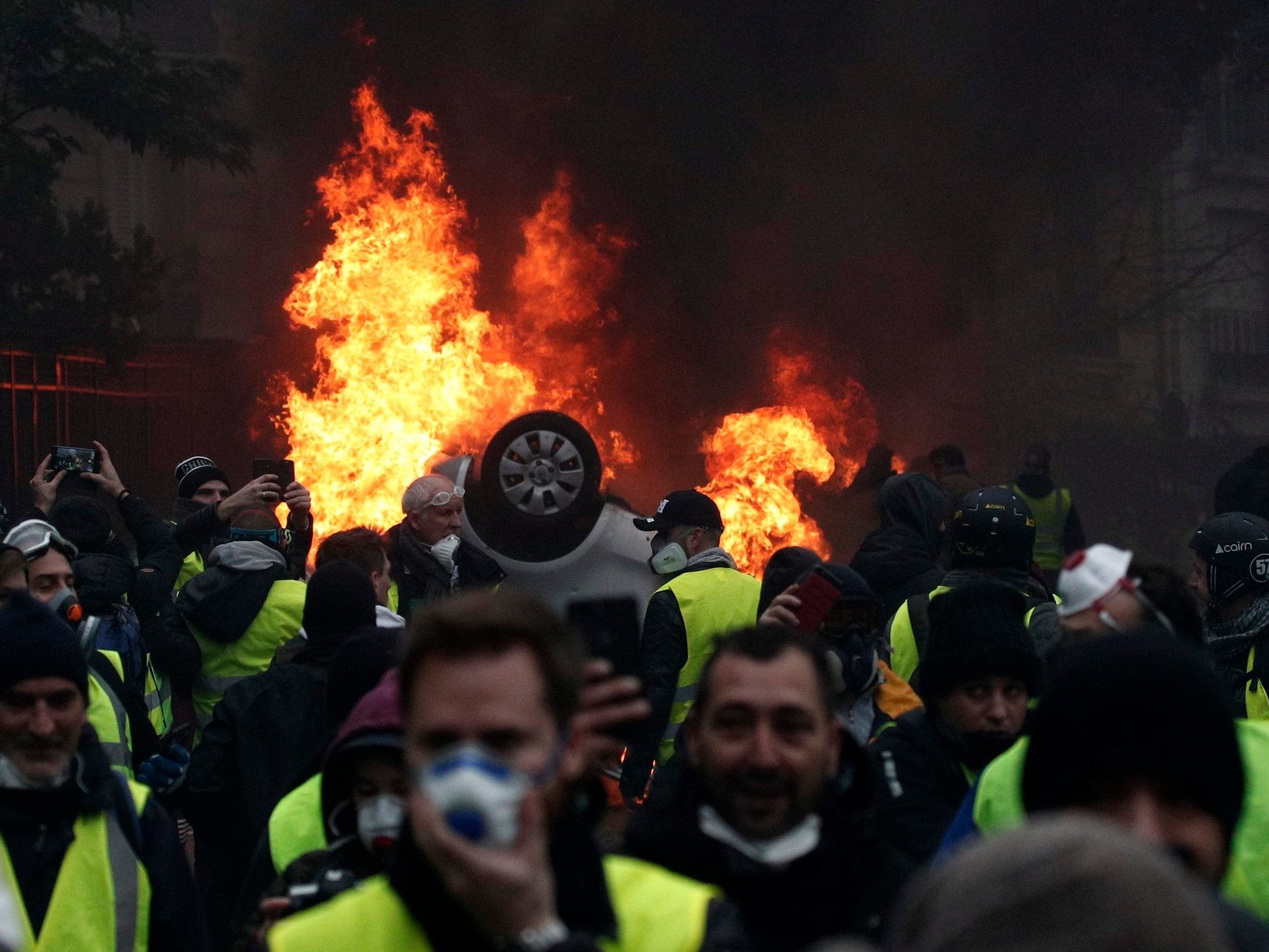 Cars burn as protesters wearing yellow vests (gilets jaunes) clash with riot police near the Arc de Triomphe