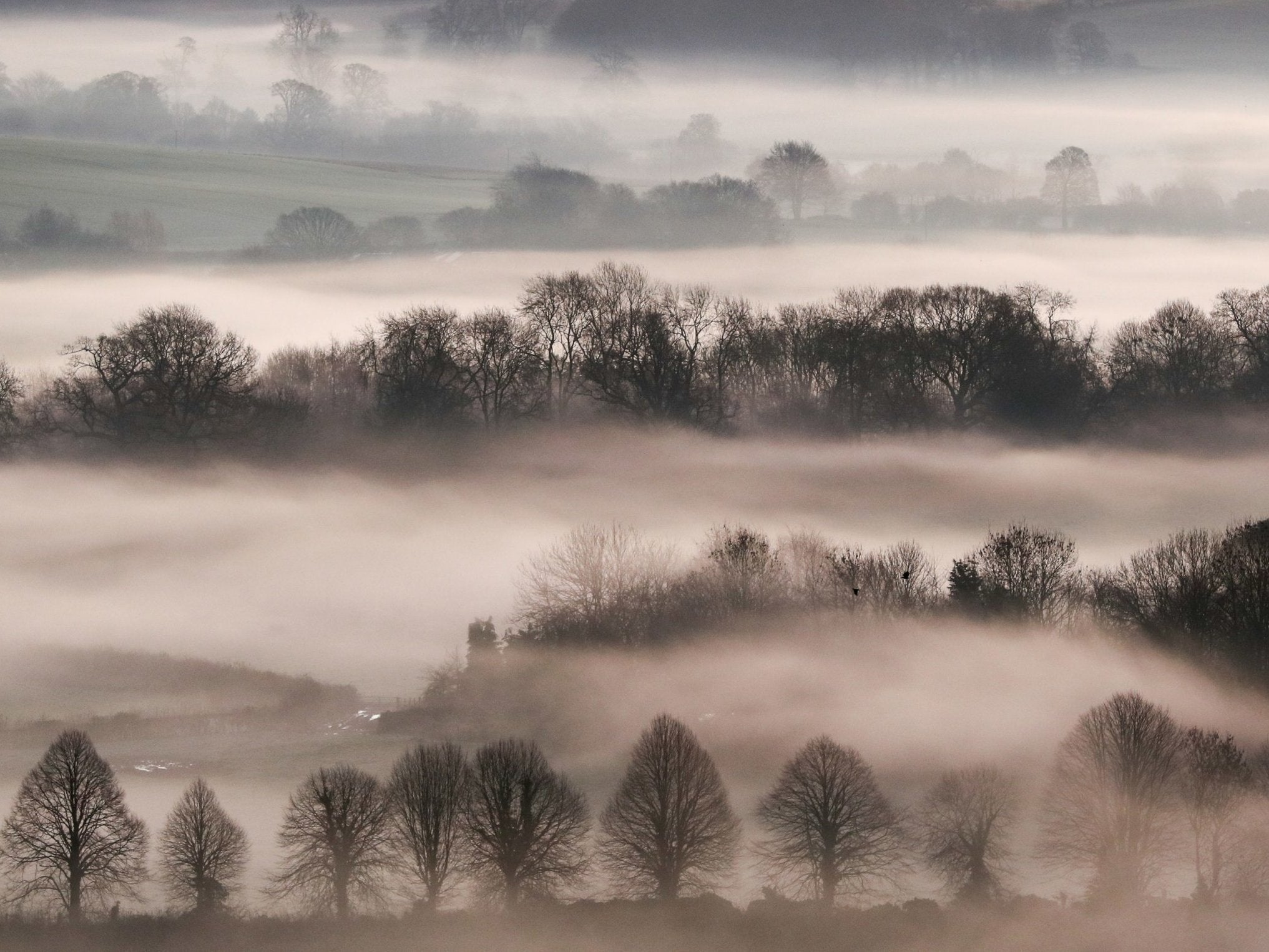 A low mist covers the fields as the sun rises over the Vale of Pewsey near Marlborough in Wiltshire