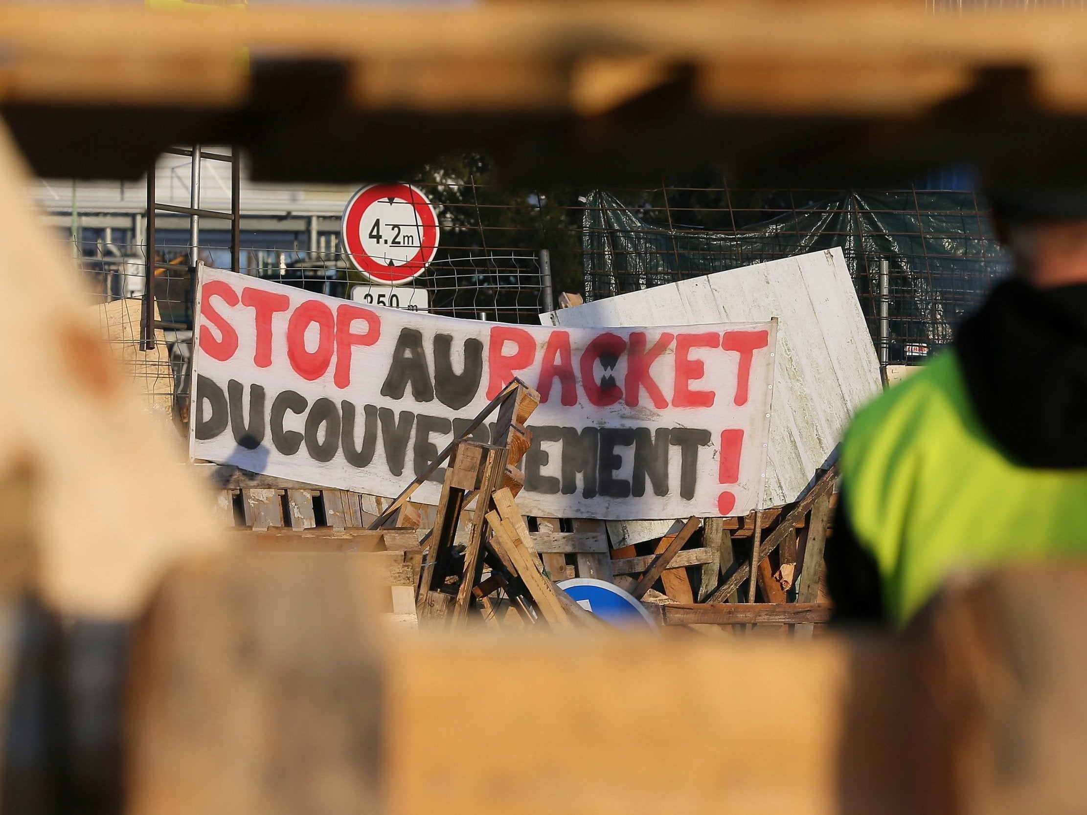 A demonstrator stands in front of a barricade set up by the yellow vests to block the entrance of a fuel depot in Le Mans, western France, on Tuesday