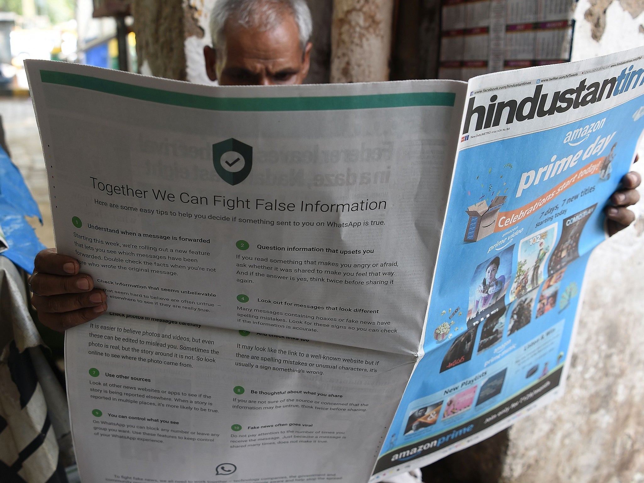 An newspaper vendor reads a paper with a full back page advertisement from WhatsApp intended to counter fake information (AFP/Getty)