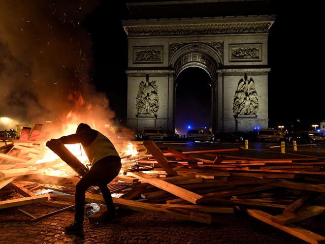 A Gilets Jaunes protester stokes a bonfire at the Arc de Triomphe