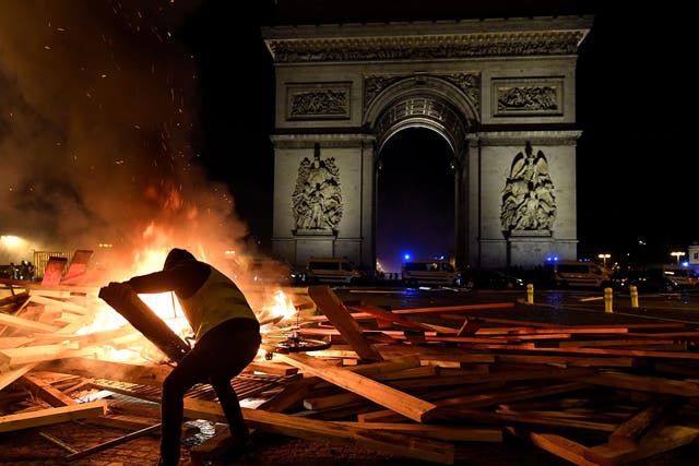 A Gilets Jaunes protester stokes a bonfire at the Arc de Triomphe