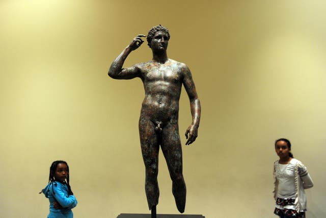 Visitors look on 18 April, 2011 at a statue of the Victorious Youth, which was recovered from a first-century BC shipwreck in the Adriatic Sea off the coast of Italy, at the Getty Villa Museum in Malibu, California.