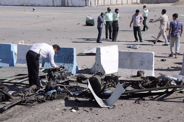 An officer inspects the vehicle wreckage outside a police station