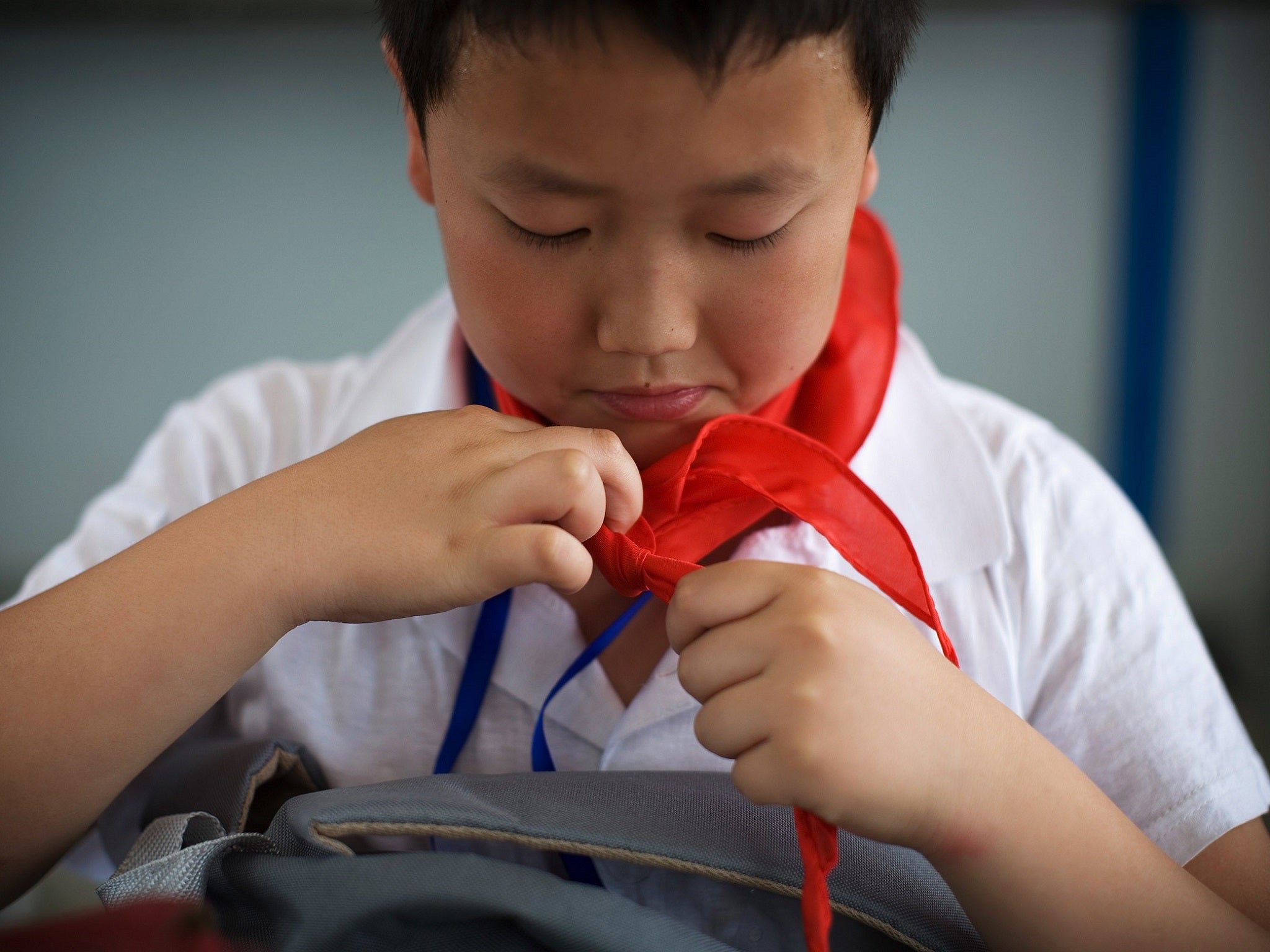 A member of the Young Pioneers ties his red scarf.
