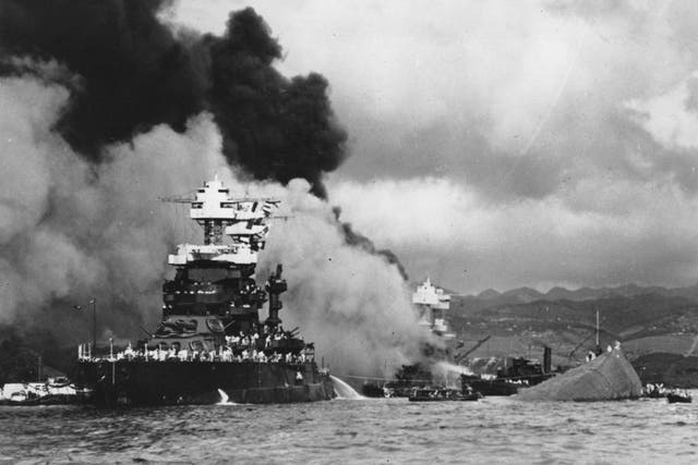 Part of the capsized USS Oklahoma (right) as the battleship USS West Virginia (centre) begins to sink after suffering heavy damage, while the USS Maryland (left) is still afloat in Pearl Harbour, Oahu, Hawaii