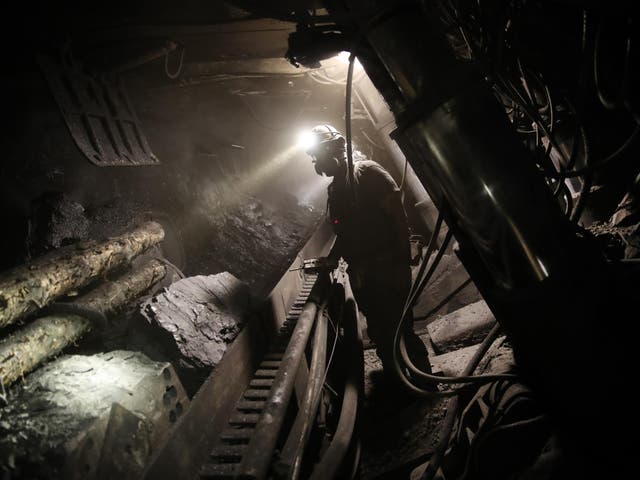 A Polish coal miner monitors a machine grinding coal from a wall approximately 1000 meters below the surface at the KWK Pniowek coal mine