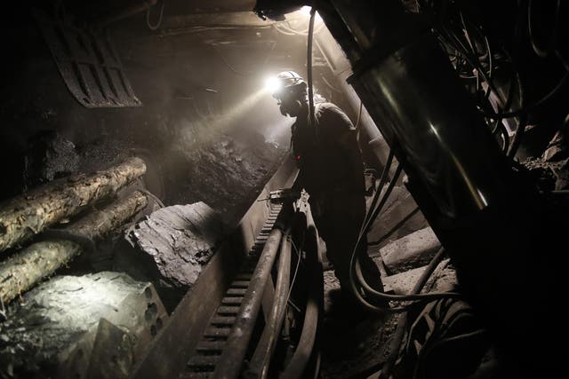 A Polish coal miner monitors a machine grinding coal from a wall approximately 1000 meters below the surface at the KWK Pniowek coal mine