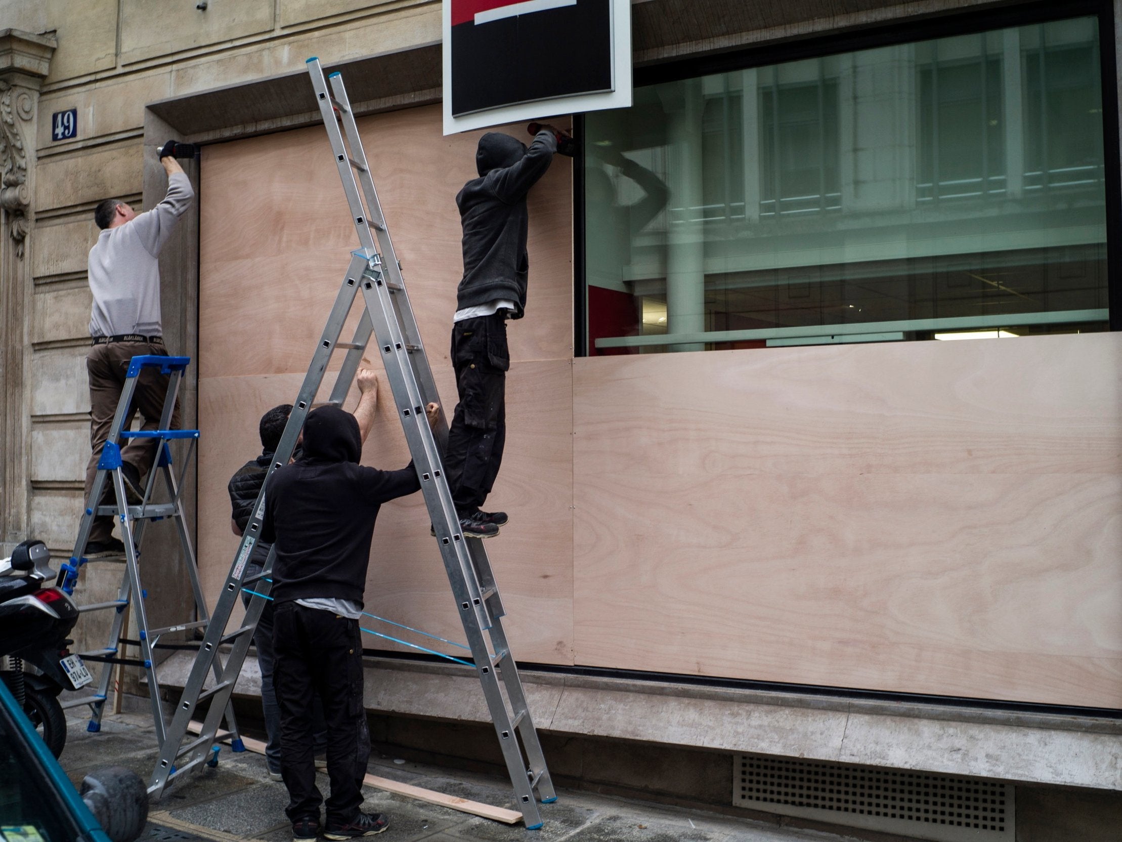 Men install wooden panels to protect a bank ahead of the national anti-governmental protest to be held on 8 December by the so-called Gilets Jaunes (Yellow Vest) movement in Paris