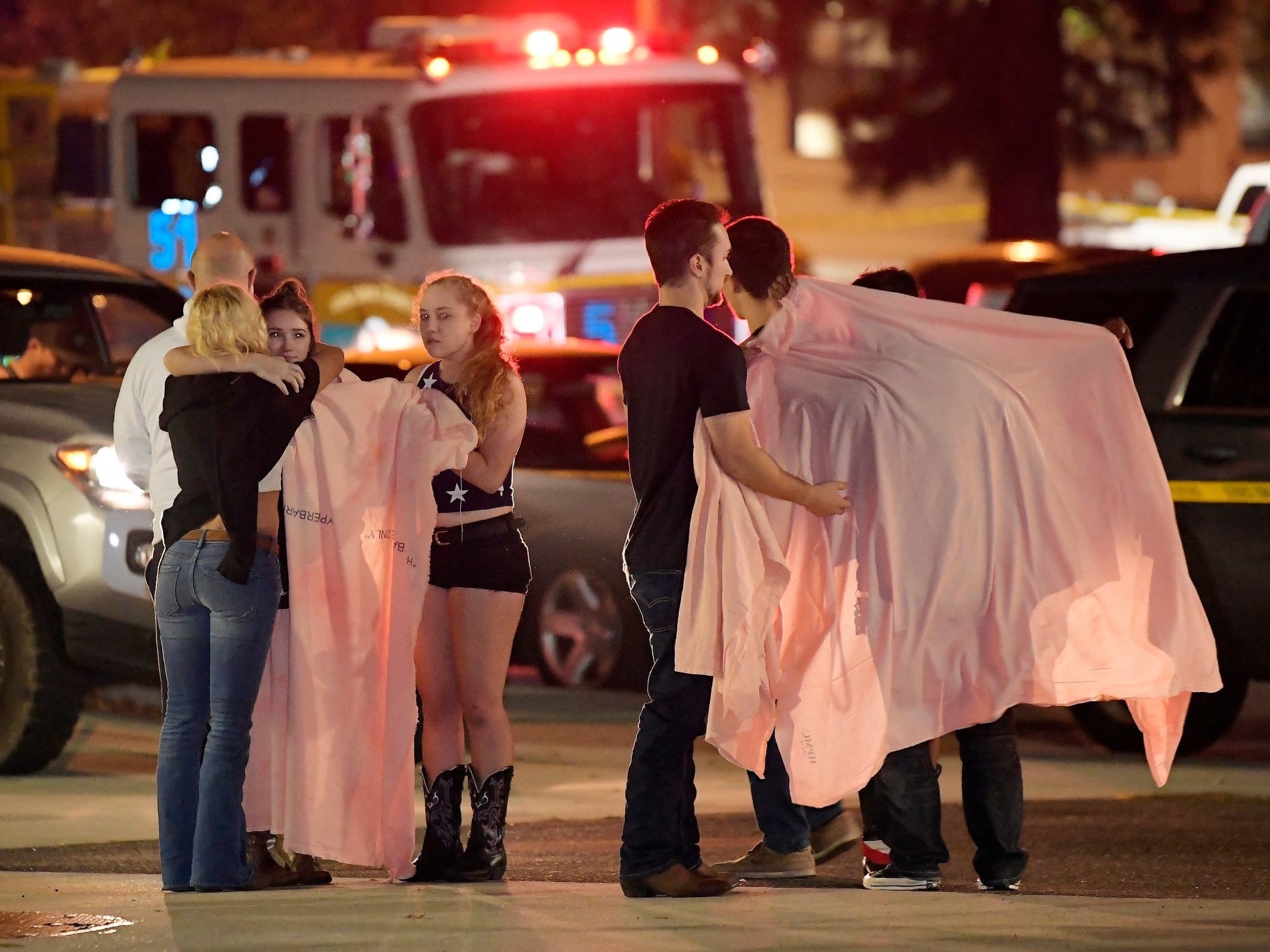 People comfort each other as they stand near the scene 8 November, 2018, in Thousand Oaks, California, where a gunman opened fire inside a country dance bar crowded with hundreds of people on "college night," killing 11 people including Sergeant Ron Helus, who rushed to the scene.