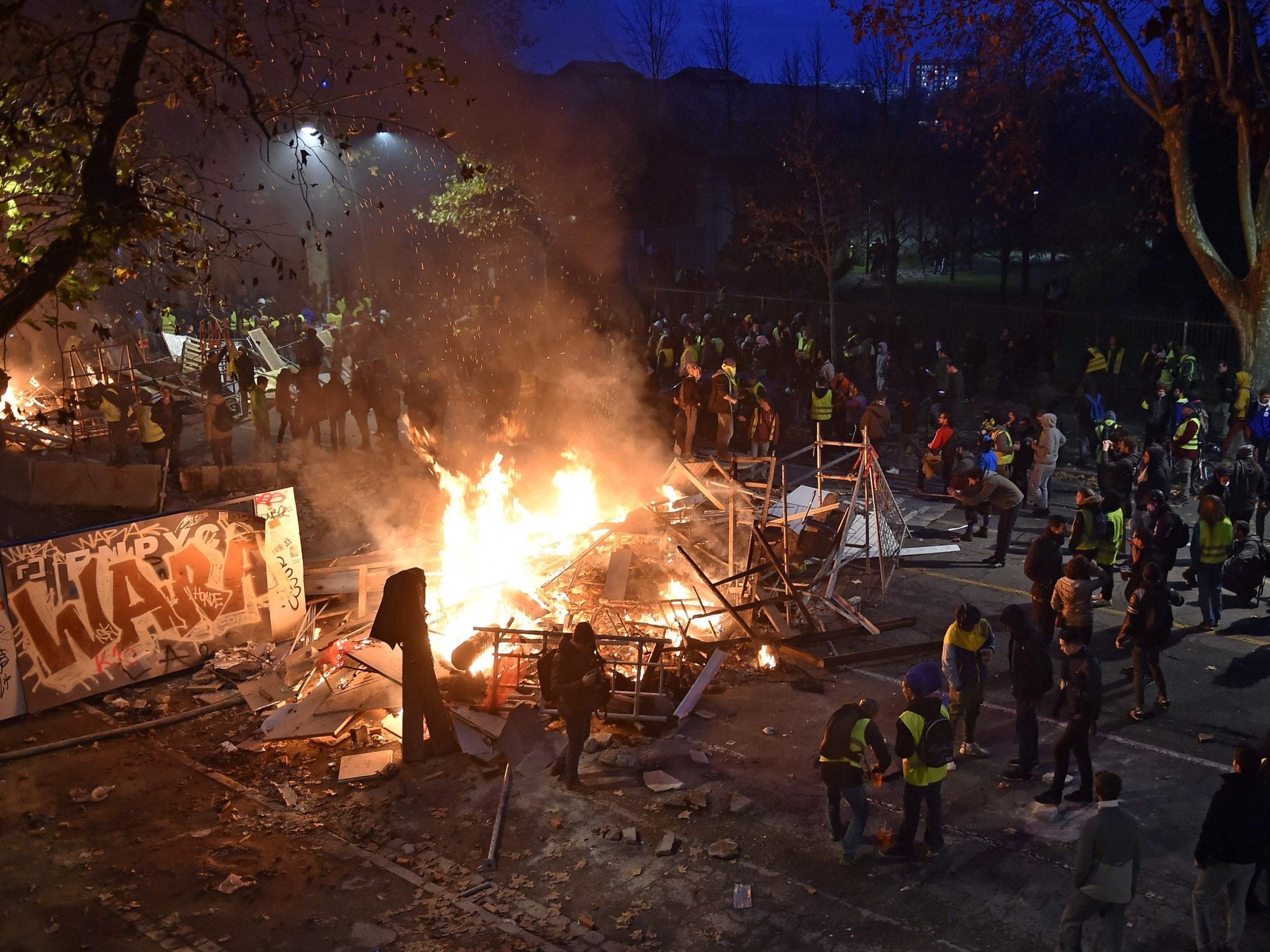 Yellow-vest protesters stand by a burning barricade in Toulouse amid demonstrations against the cost of living (AFP)