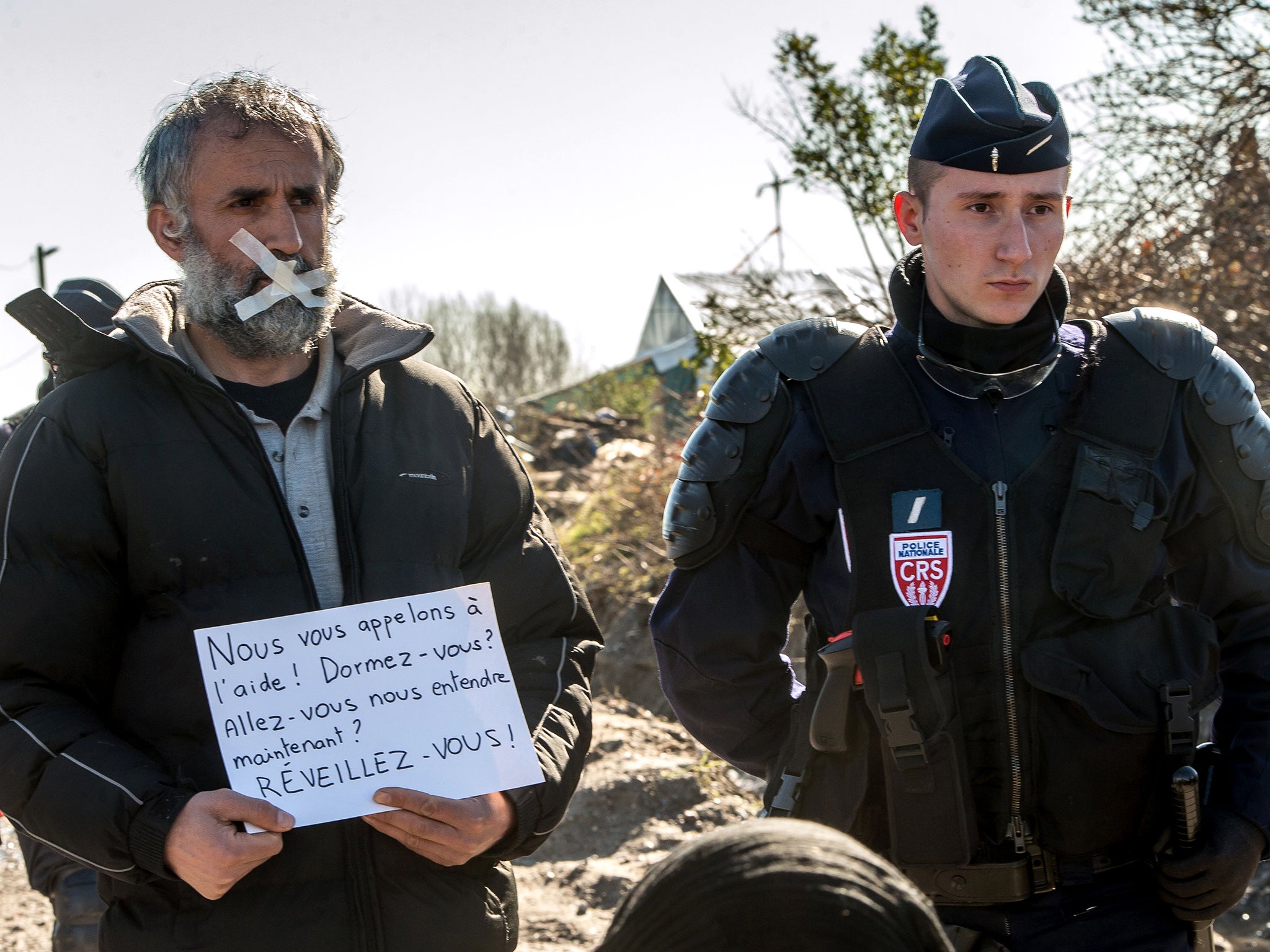 A demonstrator and anti-riot officer during a protest against the demolition of the Jungle, 2016